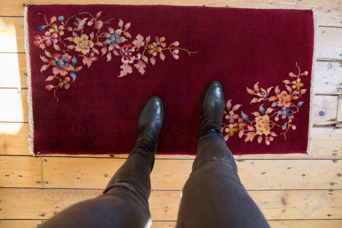 Deep red rug runner with scattered floral ornaments in beige, blue, and gold tones